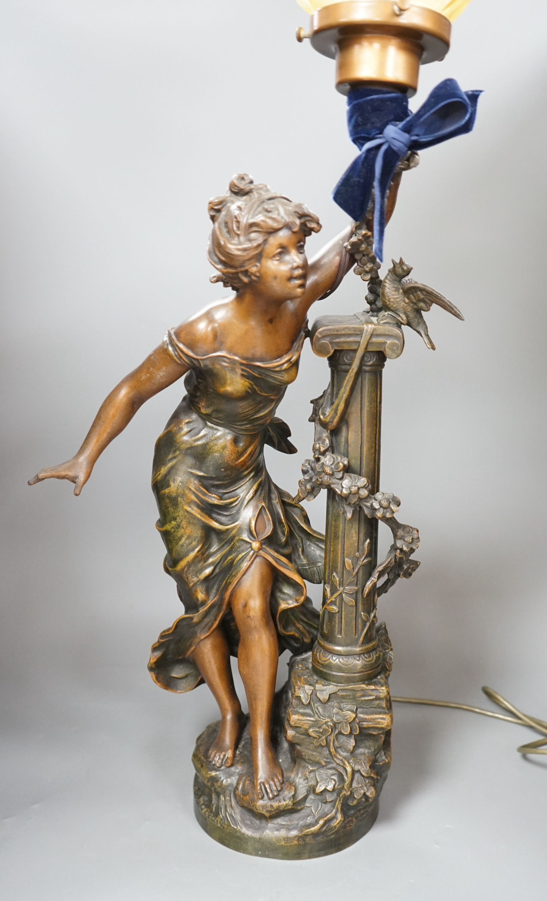 An Art Nouveau style figural lamp, with an amber glass flambe shaped shade, 77cms high including shade